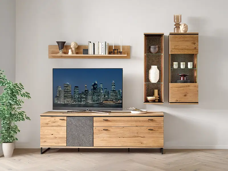 Moderner Wohnzimmerschrank aus hellem Holz mit einer großen Fernseher und dekorativen Wandregalen, neben einem Topfpflanze.